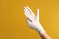 Doctor wearing medical gloves on yellow background, closeup. Space for text Royalty Free Stock Photo