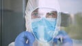 Doctor Wearing Protection Suit in Back of a Window in a Hospital Room