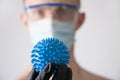 A doctor wearing protective glasses, a medical mask, and black gloves holds a mock-up of the virus Royalty Free Stock Photo