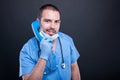 Doctor wearing scrubs holding telephone receiver and smiling Royalty Free Stock Photo