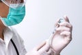 Doctor wears face mask and white medical glove hand holding flu, covid-19 liquid vaccine vial bottle and syringe for injection Royalty Free Stock Photo