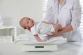 Doctor weighing cute baby in clinic