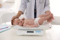 Doctor weighting cute baby in clinic. Health care