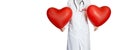 A doctor in a white coat with a badge a stethoscope holds two red large hearts. Royalty Free Stock Photo