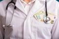 A doctor in a white coat on his shoulders with a stethoscope and money in his pocket Royalty Free Stock Photo