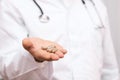 Doctor in a white coat holding pills in a hand