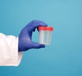 Doctor in a white coat holds a empty plastic container for urine specimen