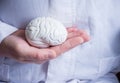 Doctor in white coat holds in his hand in palm of anatomical model of human brain. Concept photo of diagnosis, treatment and preve