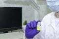 A doctor in a white coat and a hygiene mask in his office holds the bottle with yellow pills in his hand