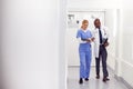 Doctor In White Coat And Nurse In Scrubs Looking At Digital Tablet In Hospital Corridor Royalty Free Stock Photo