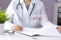 A doctor in a white coat with a pharyngoscope sits in a medical office