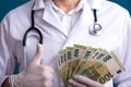 A doctor in a white coat on his shoulders a stethoscope in the hands of money Royalty Free Stock Photo