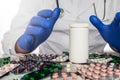 Doctor in white coat sits infront of pill boards scattered on table holding hands around blank prescription bottle. Royalty Free Stock Photo