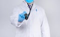 Doctor in a white coat and tie holds in his hand a black phonendoscope