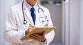 Doctor in a white coat writing medical notes on a clipboard Royalty Free Stock Photo
