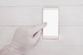 A doctor in a white glove touches his finger to a smartphone with a white blank screen. Isolated over white background Royalty Free Stock Photo