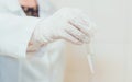 A doctor in white gloves holding a test tube with sample