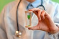 A doctor in white medical gloves holds an hourglass - a symbol of time to heal and cure. Close up