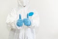 Doctor in white protective suit, medical mask and blue gloves shows a thumbs up. Epidemic, pandemic of coronavirus covid 19.