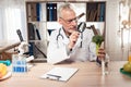 Doctor sitting at desk in office. Man is looking at broccoli with magnifying glass.