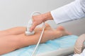 Doctor in white uniform with diagnostic equipment performs an ultrasound using a device on the legs of a female patient. Surgeon