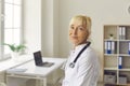 Close up portrait of senior tired female doctor looking at camera while standing in medical office. Royalty Free Stock Photo
