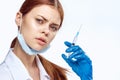 Doctor woman in blue gloves with stethoscope nurse with glasses injection syringe laboratory light background Royalty Free Stock Photo