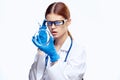 Doctor woman in blue gloves with stethoscope nurse with glasses injection syringe laboratory light background Royalty Free Stock Photo