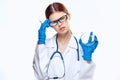 Doctor woman in blue gloves with stethoscope nurse with glasses injection syringe laboratory light background