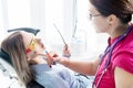 Doctor. Woman. Dentist talking to a young patient sitting on the dentist`s chair in the medical office. Shows in the