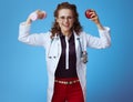 Doctor woman with dumbbell and apple showing biceps