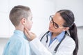 Doctor woman examining tonsils of young boy in medical office