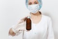 Doctor woman in face mask, sterile hat, gloves holding liquid medicine in bottle isolated on white background. Female Royalty Free Stock Photo