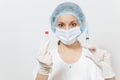 Doctor woman in face mask, sterile hat, gloves holding liquid medicine in bottle with syringe with needle isolated on Royalty Free Stock Photo