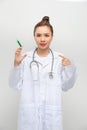 Doctor woman holding syringe with hand pointing, shocked with shame and surprise face, angry and frustrated. Fear and upset for