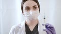 Doctor woman with a mask, blue examination gloves and a syringa with vaccine inside