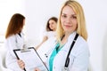 Doctor woman or nurse in a hospital office with her colleague and patient in the background. Healthcare and medicine Royalty Free Stock Photo