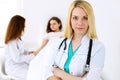 Doctor woman or nurse in a hospital office with her colleague and patient in the background. Healthcare and medicine Royalty Free Stock Photo