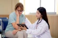Doctor woman and senior patient explaining and looking on tablet computer for diagnostics and examining disease. Royalty Free Stock Photo