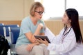 Doctor woman and senior patient talking and looking on tablet computer for diagnostics and examining disease at hospital. Royalty Free Stock Photo