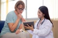 Doctor woman and senior patient talking and looking on tablet computer for diagnostics and examining disease. Royalty Free Stock Photo