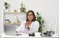 Doctor woman sitting in her desk of medical office holding and showing stethoscope while looking at camera Royalty Free Stock Photo