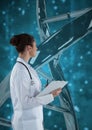 Doctor woman standing with 3D DNA strand against blue background Royalty Free Stock Photo