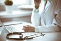 Doctor woman using laptop computer while sitting at the desk near window in hospital. Medicine and health care concept Royalty Free Stock Photo