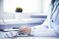 Doctor woman using laptop computer while sitting at the desk near window in hospital. Medicine and health care concept Royalty Free Stock Photo