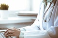 Doctor woman using laptop computer while sitting at the desk near window in hospital. Medicine and health care concept Royalty Free Stock Photo