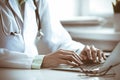 Doctor woman using laptop computer while sitting at the desk near window in hospital. Medicine and health care concept Royalty Free Stock Photo