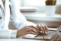 Doctor woman using laptop computer while sitting at the desk near window in hospital. Medicine and health care concept Royalty Free Stock Photo