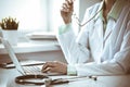 Doctor woman using laptop computer while sitting at the desk near window in hospital. Medicine and health care concept Royalty Free Stock Photo