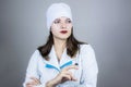 doctor woman in white coat with dark hair in medical blue mask holds syringe in hands